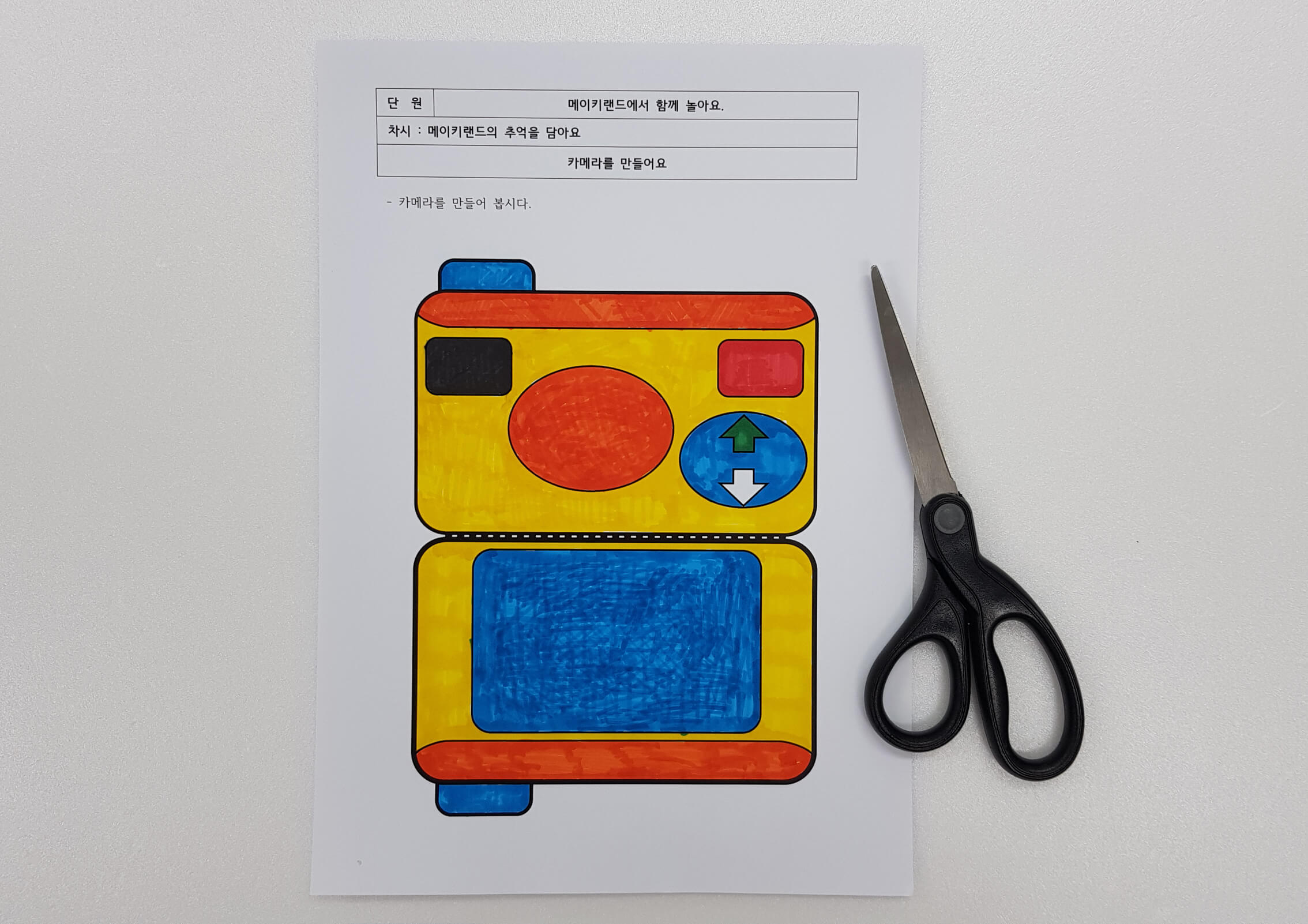 색칠한 카메라 도안을 가위로 오리는 모습