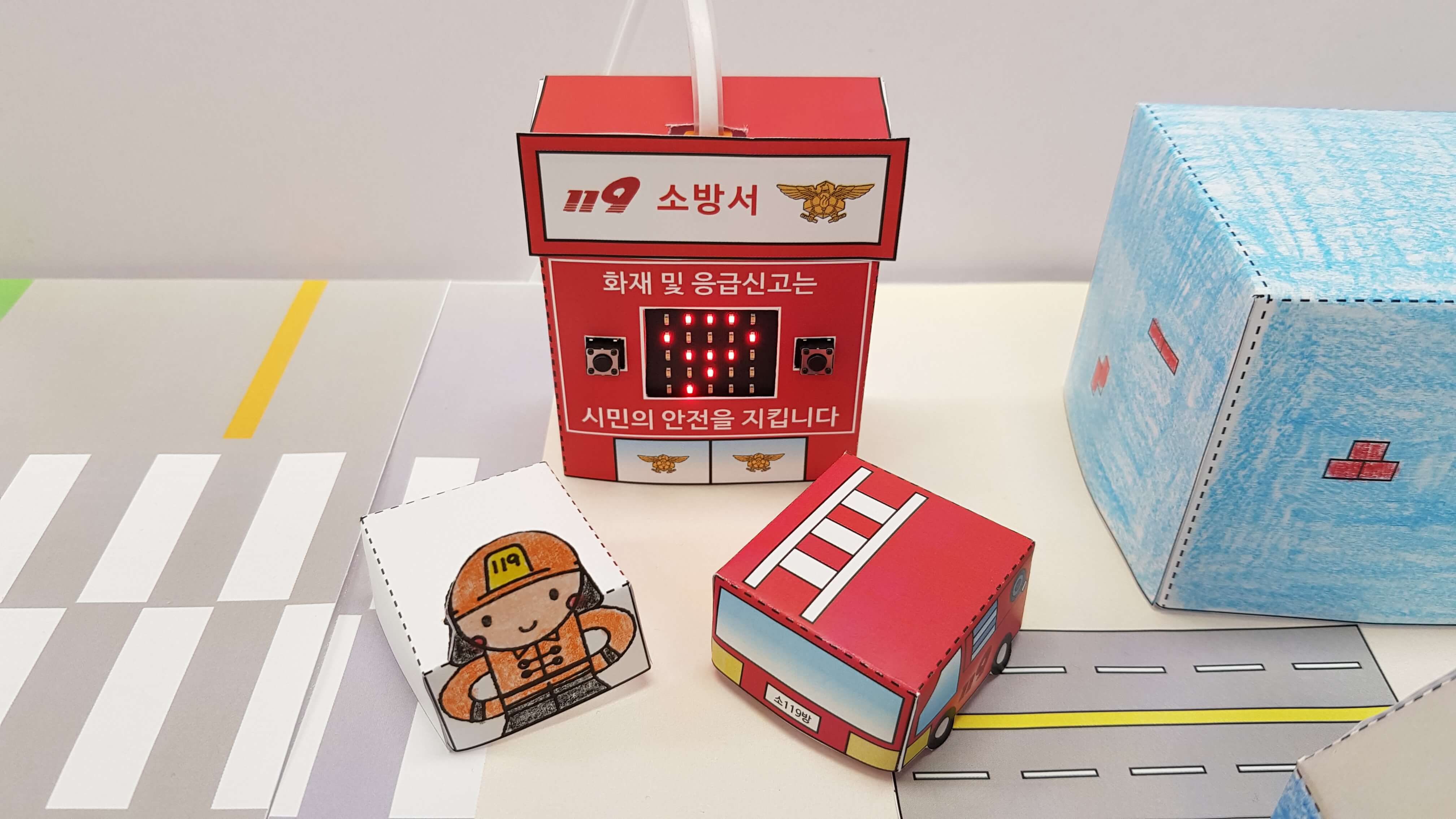 마을 소방서 앞에 소방관과 소방차를 배치한 모습
