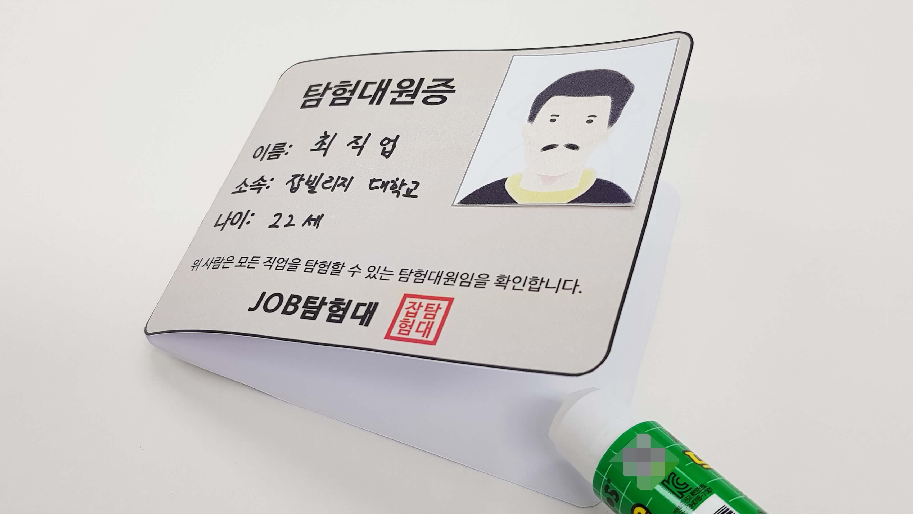 탐험 대원증을 반으로 접고 풀을 붙이는 모습